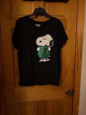 Peanuts Black Tee with Snoopy Holding Green Shamrock Graphic